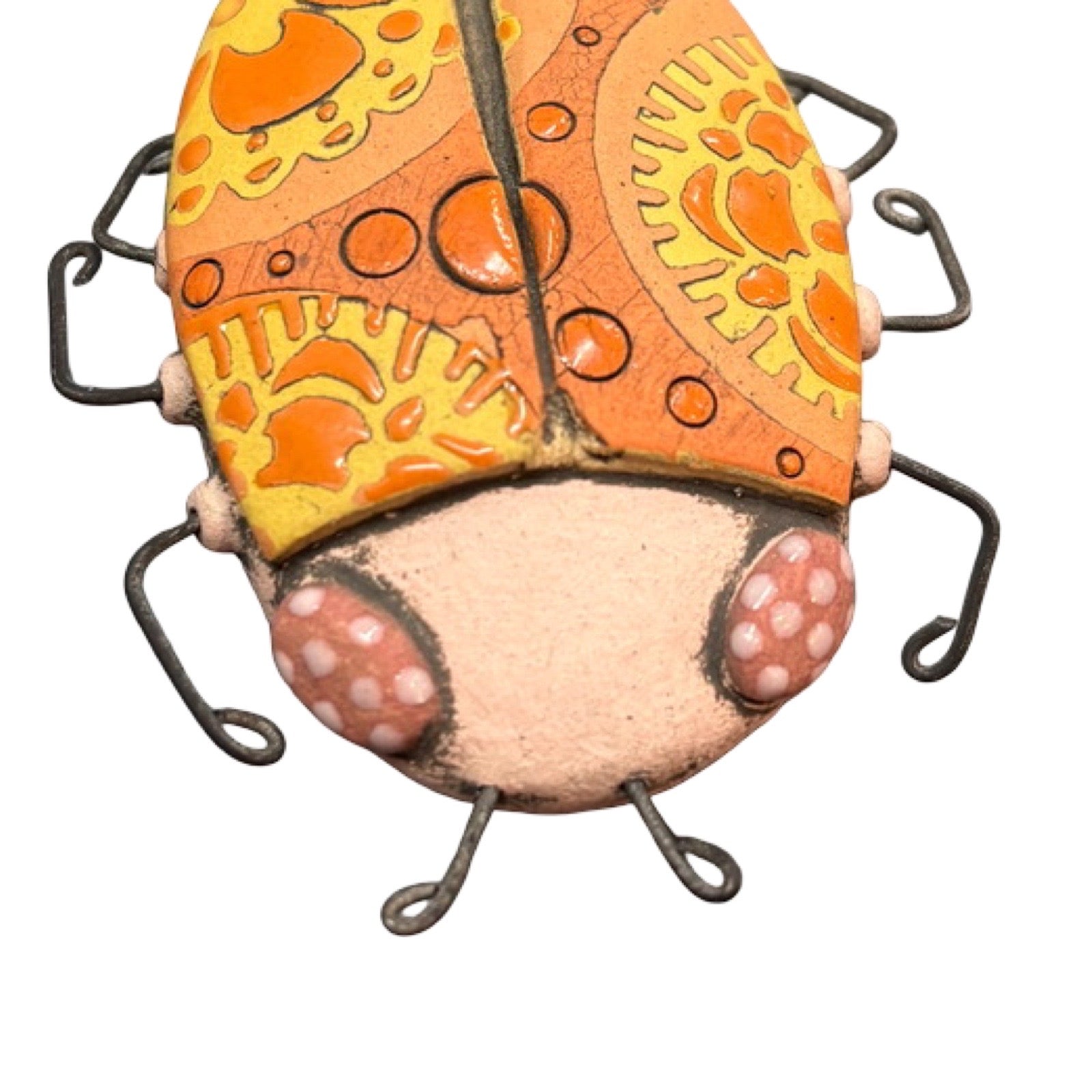 An oval ceramic beetle in orange with orange and yellow flowers and wire legs.