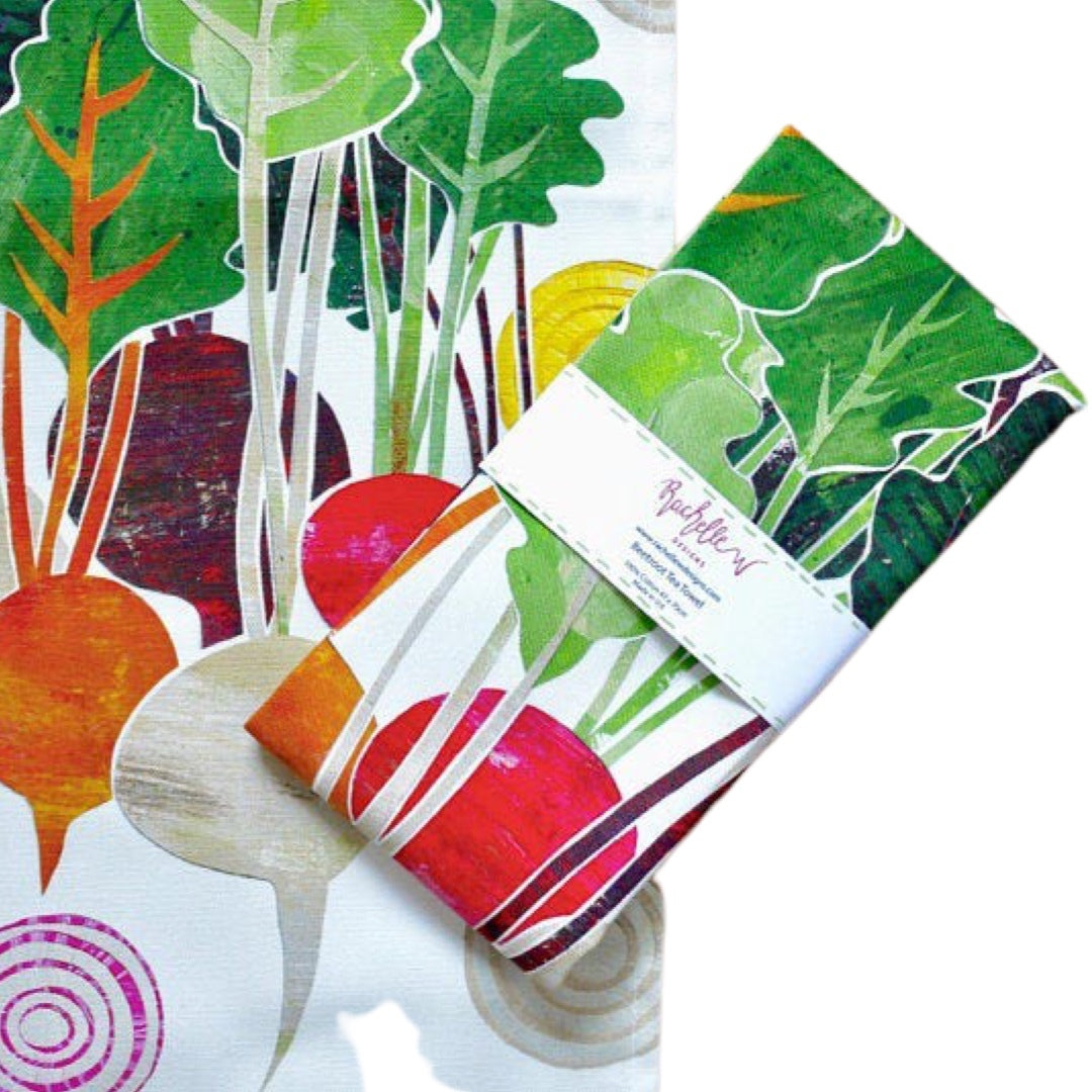 Folded beetroot tea towel with purple, pink, orange and cream beetroots with green leaves on a white background.