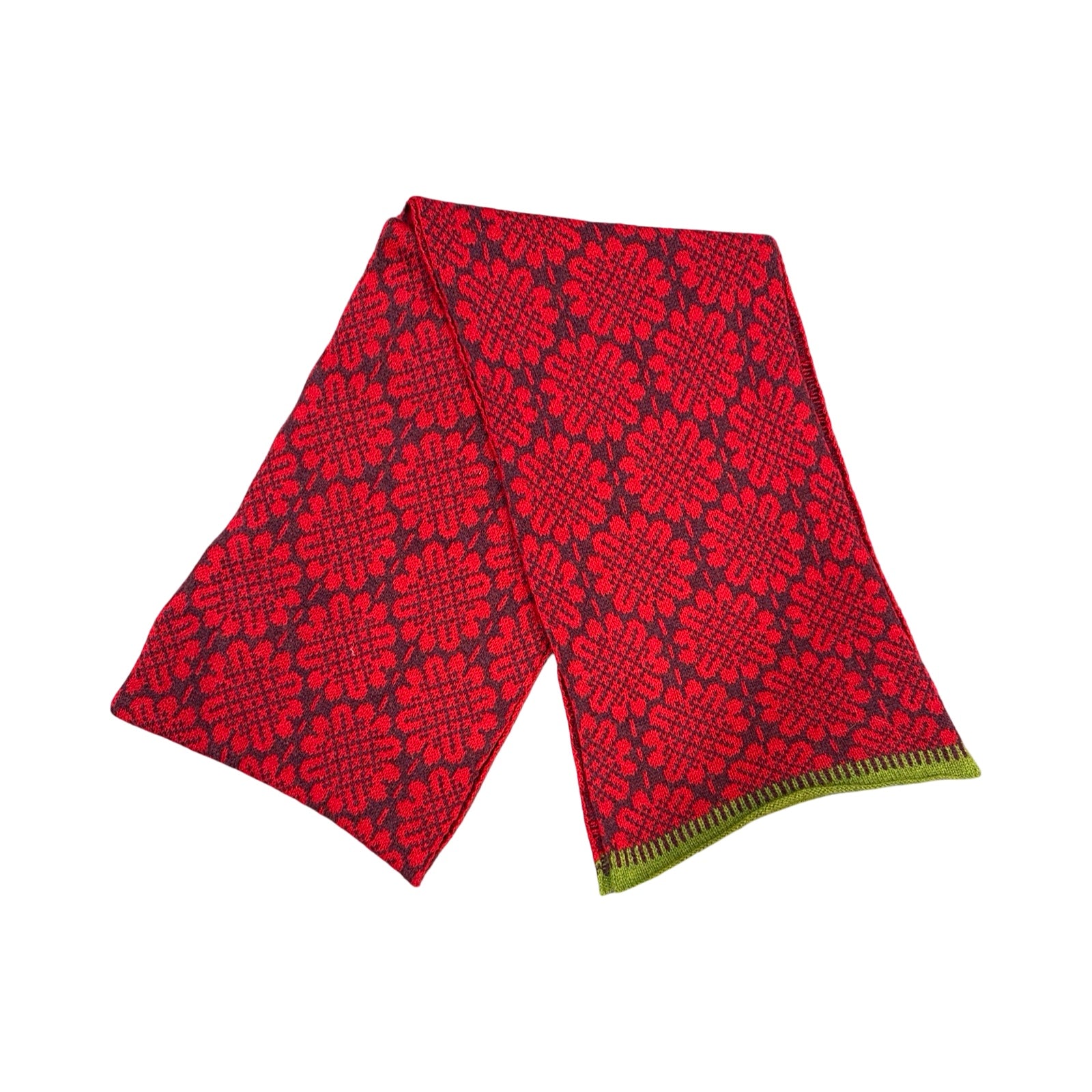 A 100% lambswool knitted scarf with a red daisy pattern against a plum background with contrasting green edges.