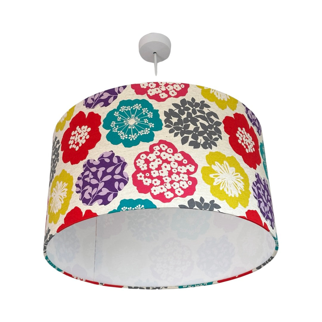 Drum lampshade covered in bright floral fabric on a white background