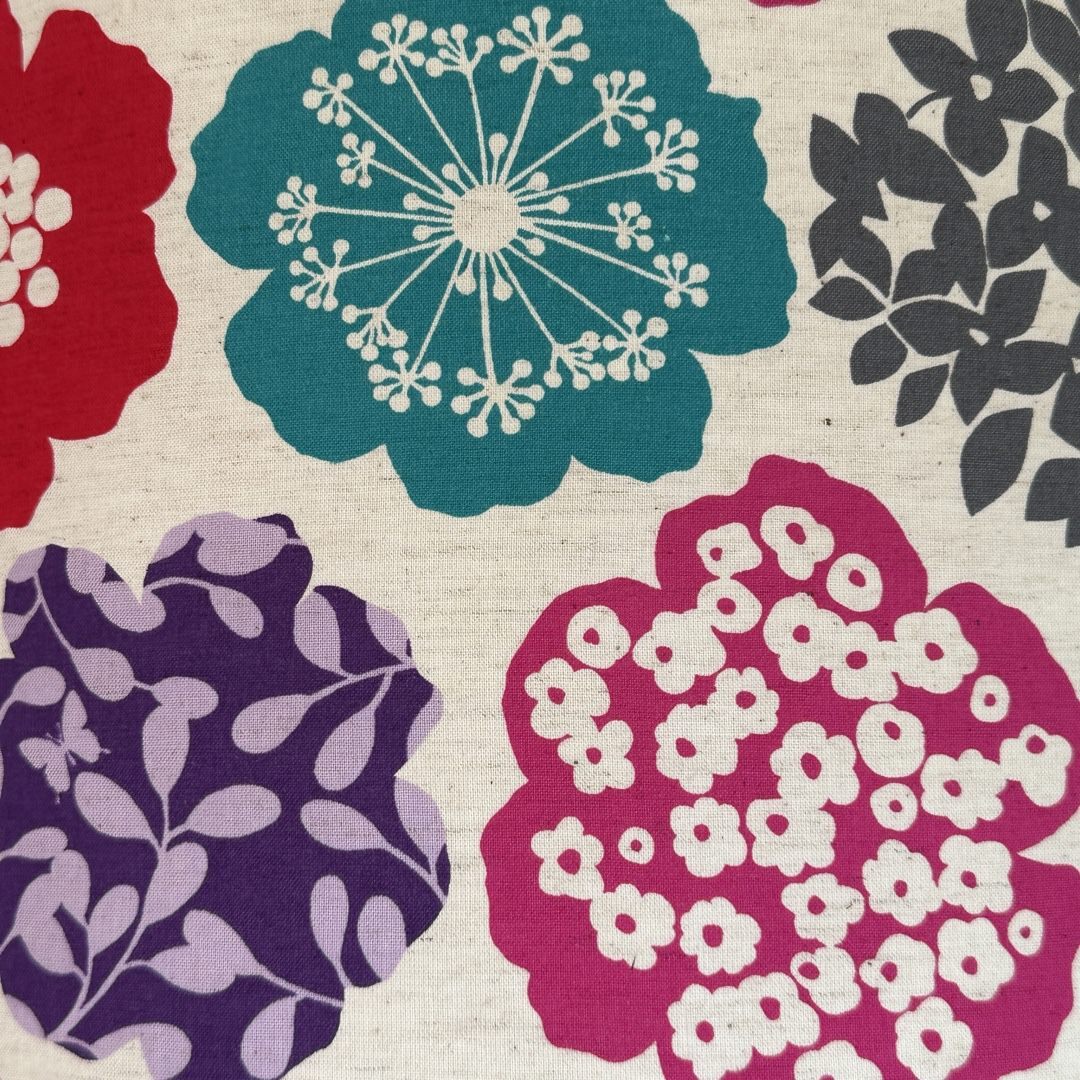 cream fabric with big turquoise, grey, purple and pink flowers.