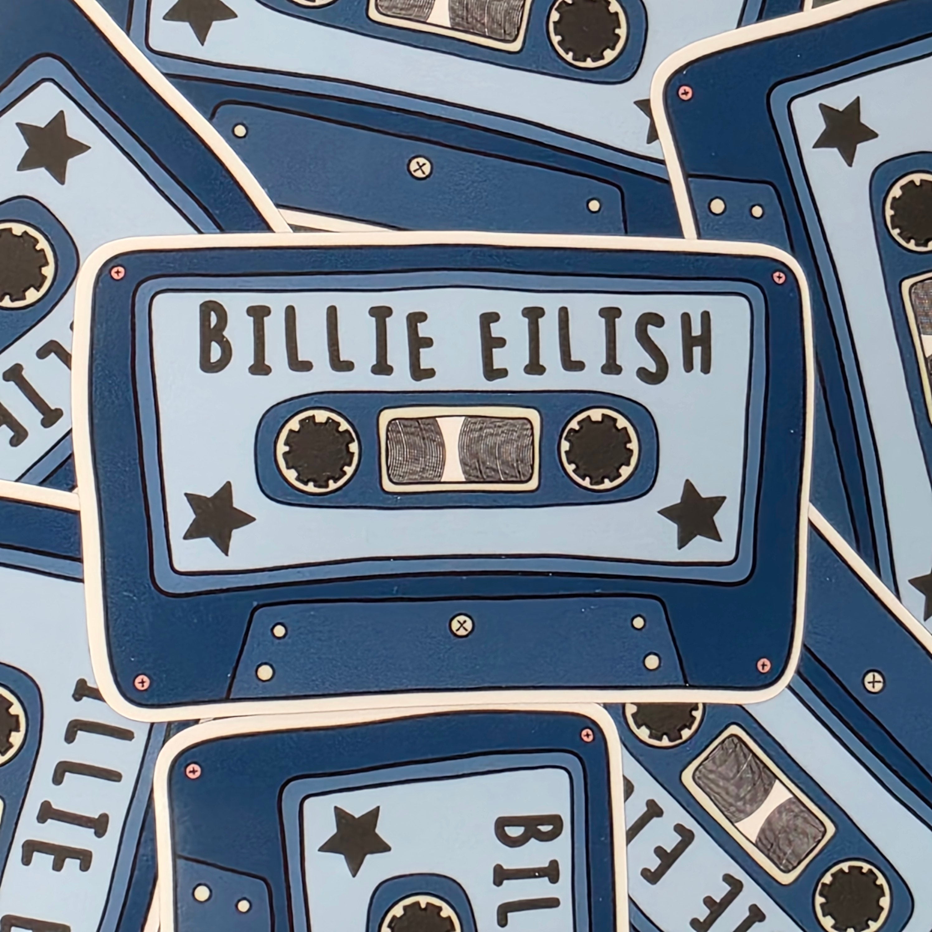 A rectangular-shaped sticker featuring an illustration of a retro cassette tape in dark and light blue with the title 'Billie Eilish'. 