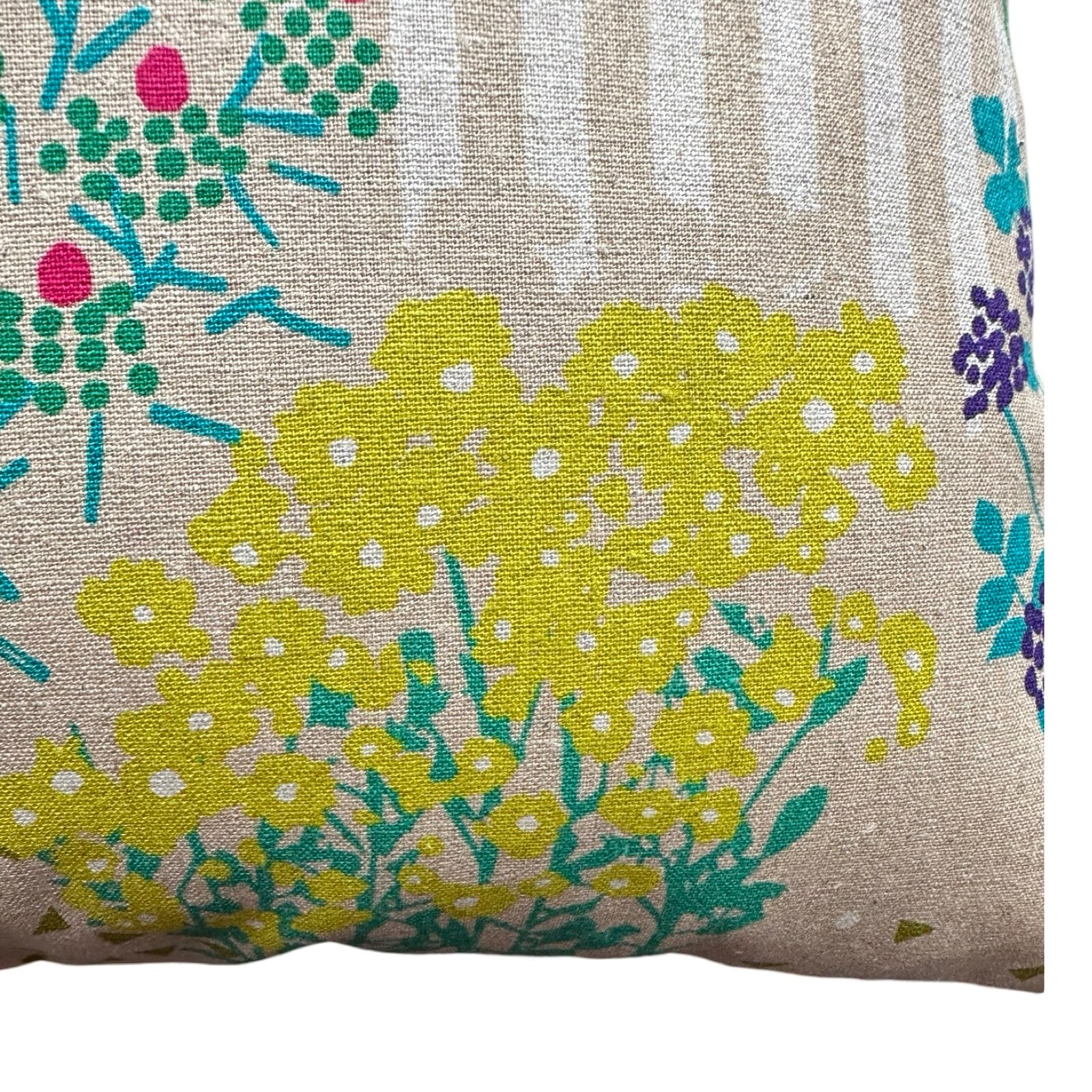 Close up of a cotton/linen fabric cushion cover with a burst of yellow blossom, green leaves and white stripes.