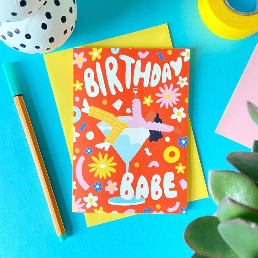 Birthday card with colorful design on a blue background with stationery items.