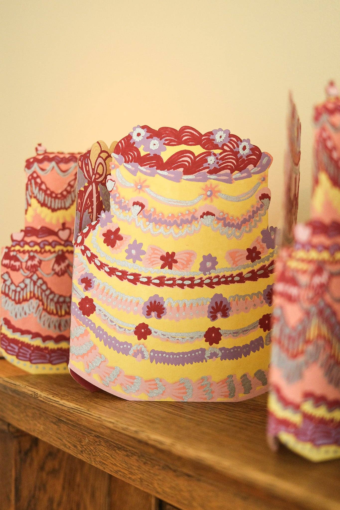 Decorative paper cake garland on a wooden surface with a plain background.