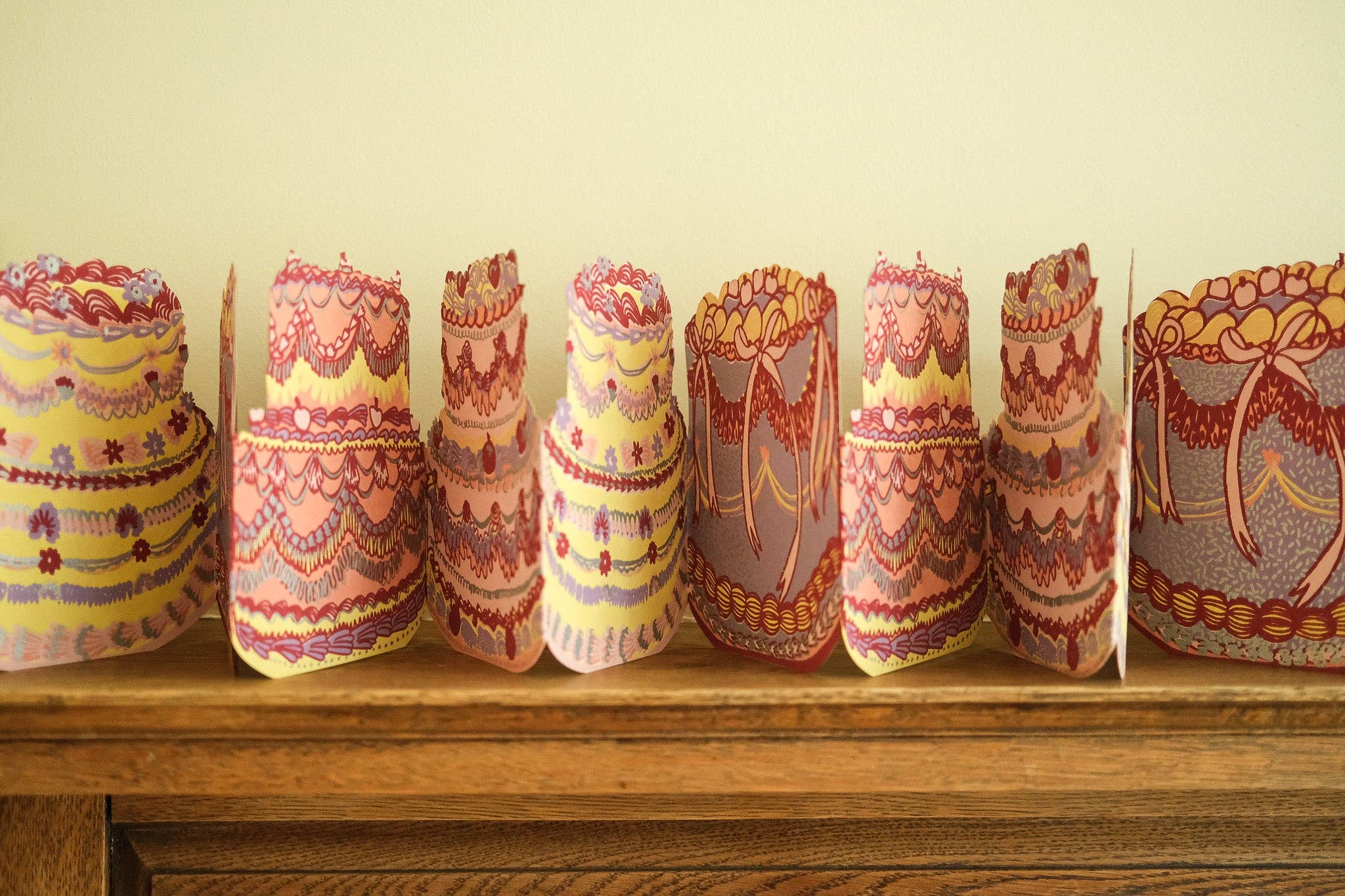 Decorative paper cake garland on a wooden surface with a plain background.