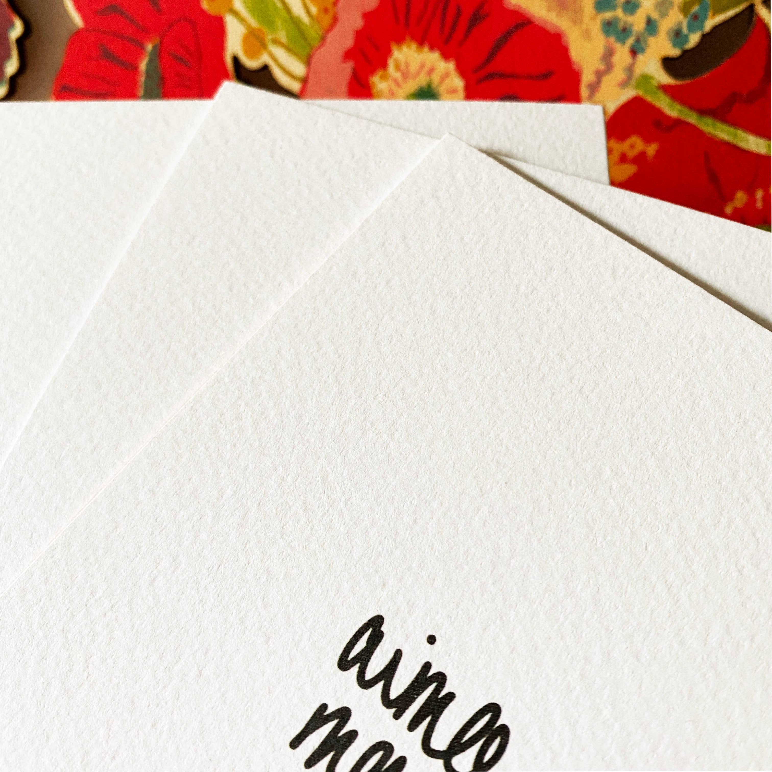 White card with 'aimee' printed on it, placed on a colourful floral background.