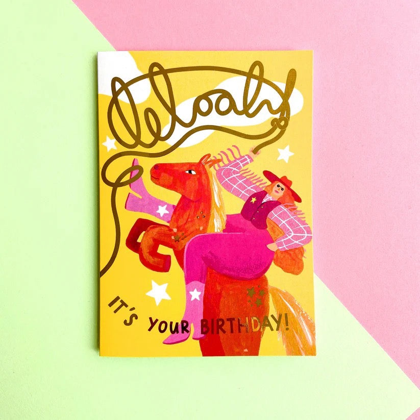 Birthday card with colorful illustration of a person on a horse and 'Happy Birthday!' text on a yellow background.