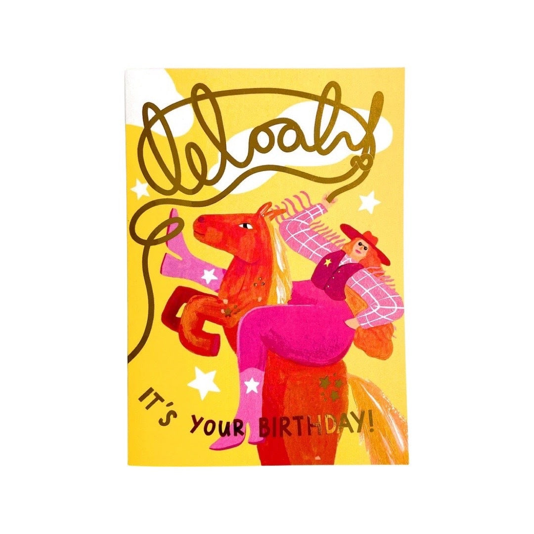 Birthday card featuring an illustration cowgirl wearing pink trousers and a checked shirt riding a red horse and the text 'Woah It's Your Birthday' in gold, all on a yellow background.