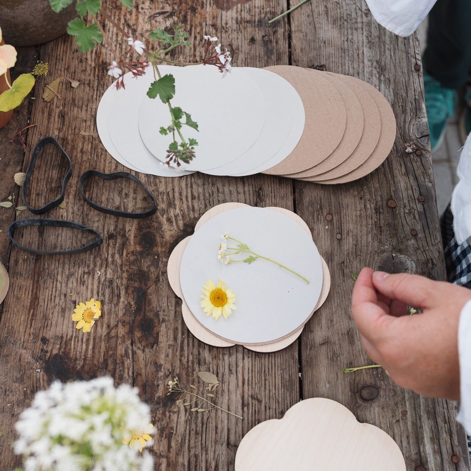 Handmade paper flowers and materials on a wooden surface.