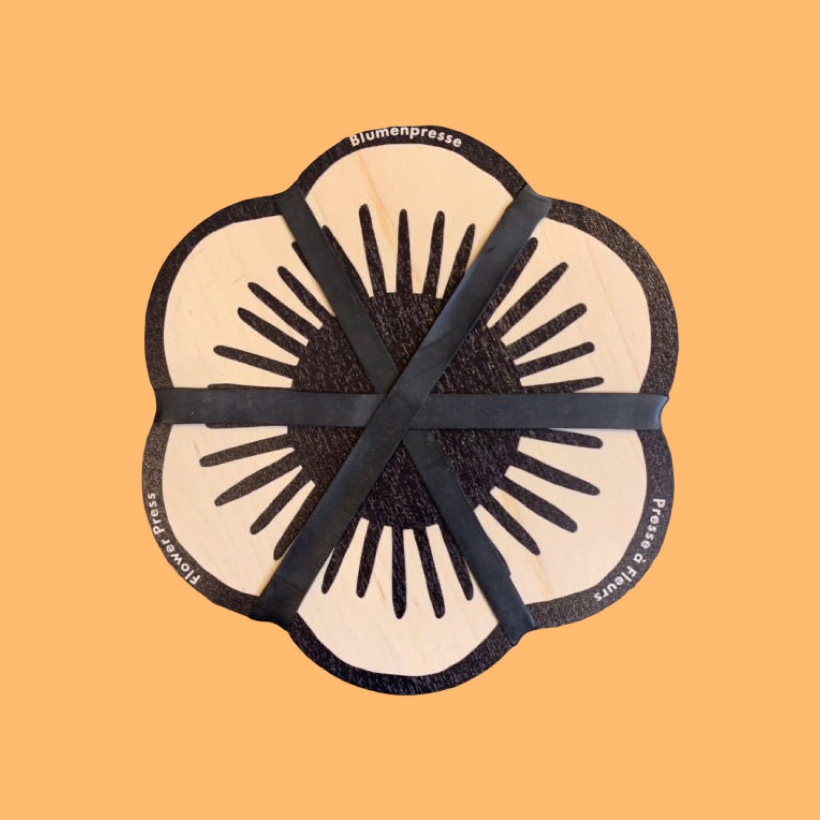 Flower-shaped black and beige press tool on a peach background.