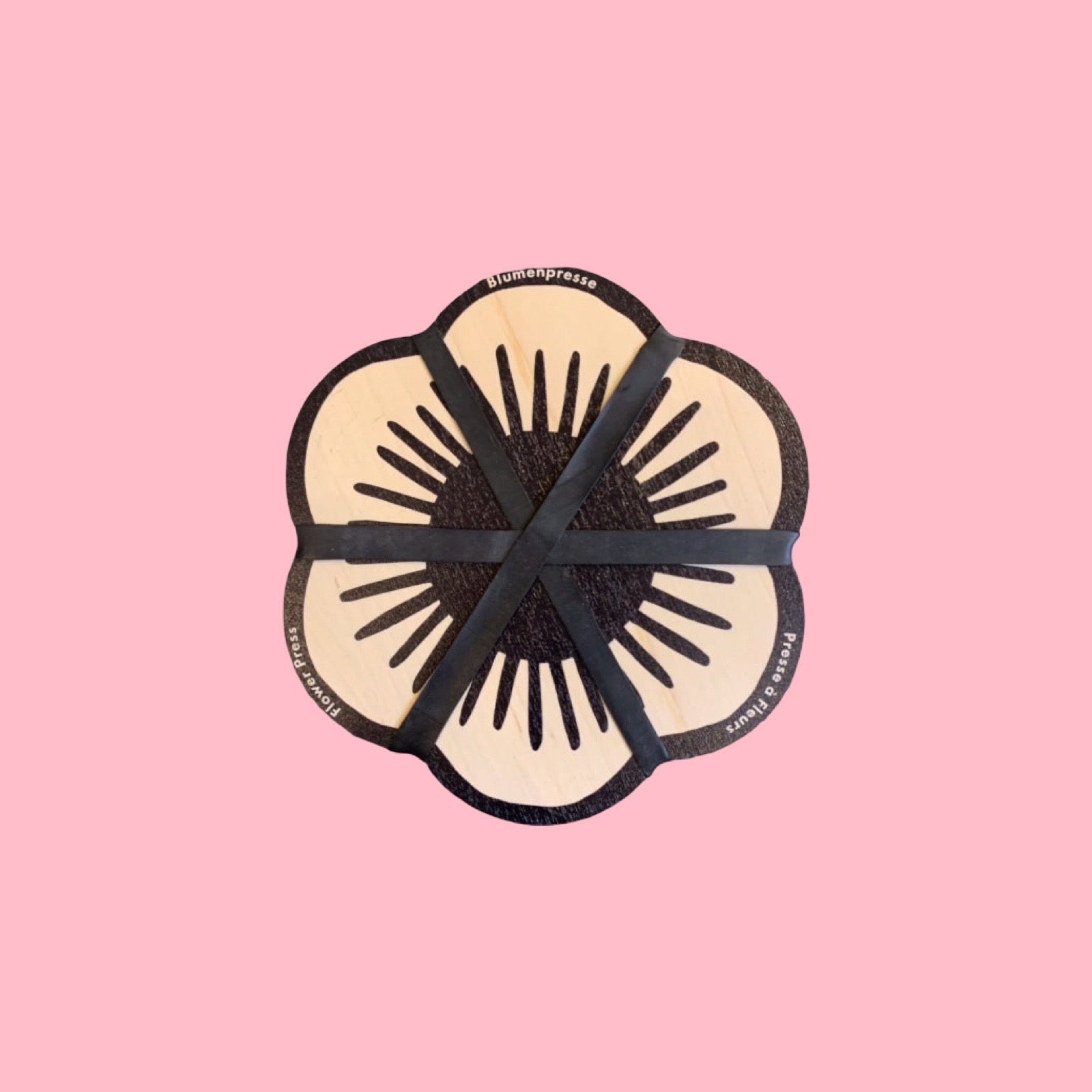 Floral-shaped product with black accents on a pink background.
