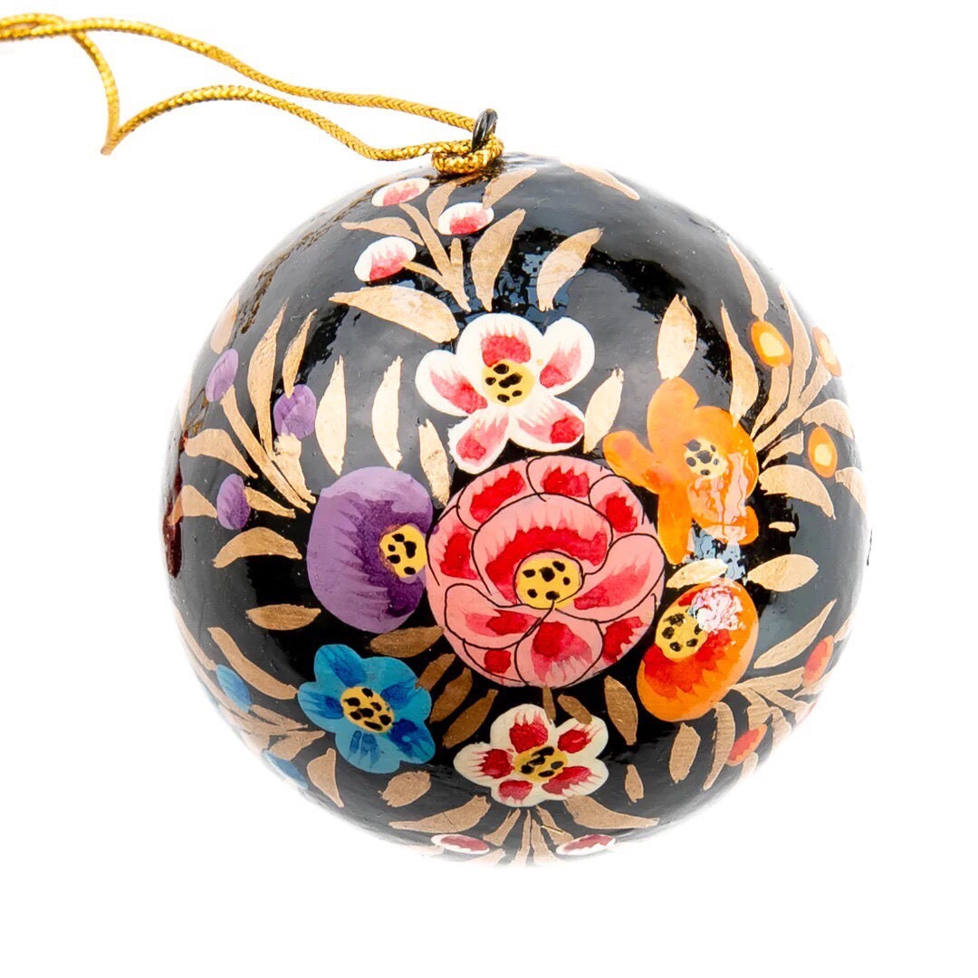 A round papier mache bauble in black with a colourful floral design.