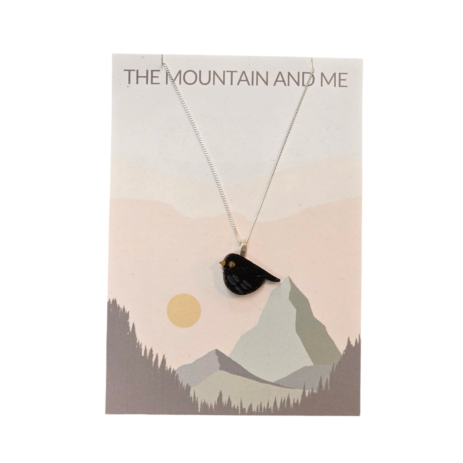 A bird-shaped bamboo pendant, painted like a blackbird, with a sterling silver chain on a branded backing card.