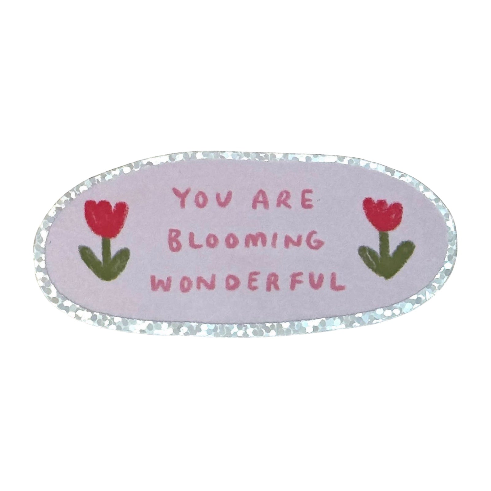 An oval-shaped decorative sticker with a silver glitter border, featuring the text 'YOU ARE BLOOMING WONDERFUL' in pink lettering on a light lavender background, flanked by two red tulips with green leaves.