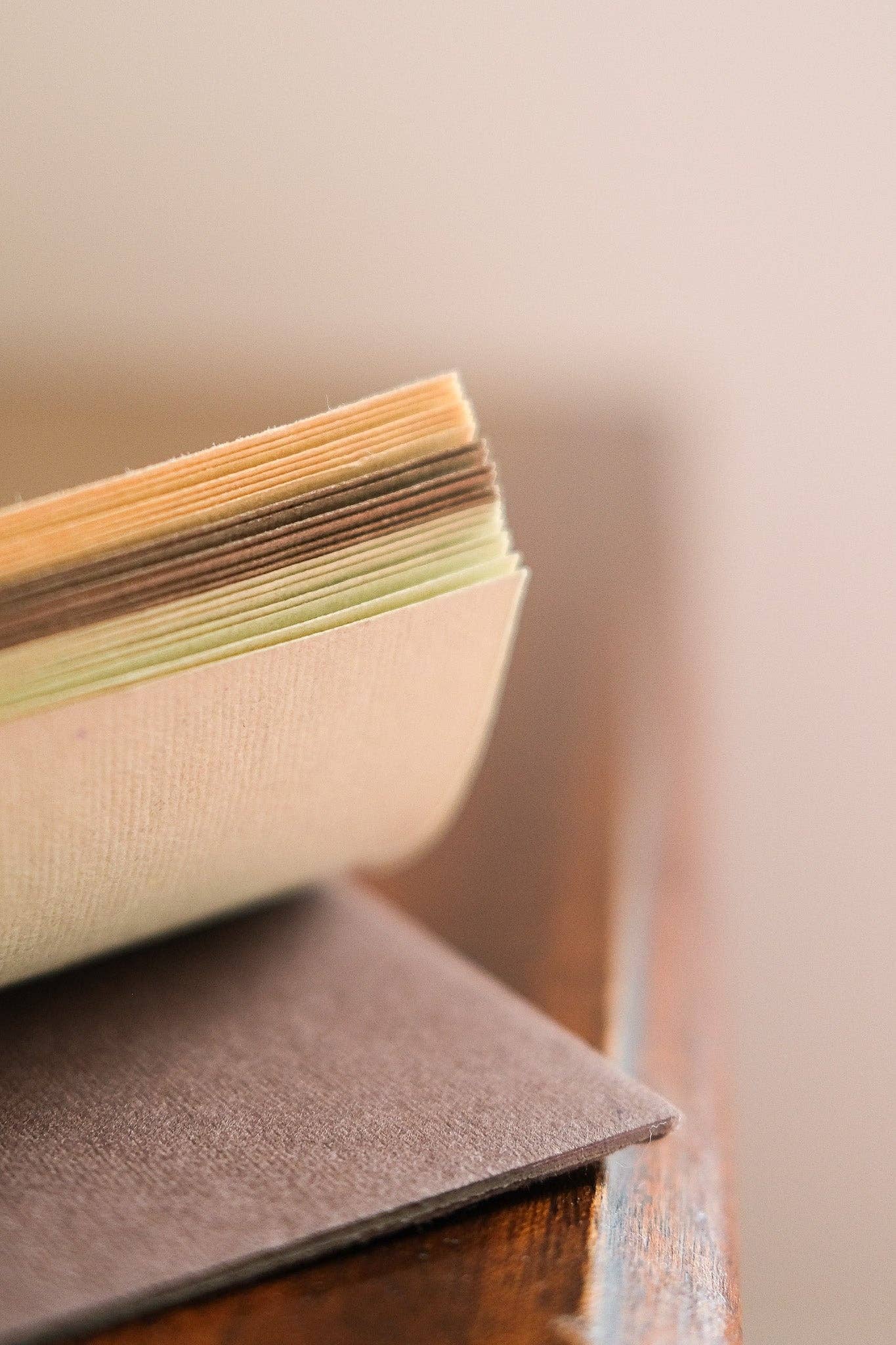 Stack of colourful paper sheets on a wooden surface with a blurred background.
