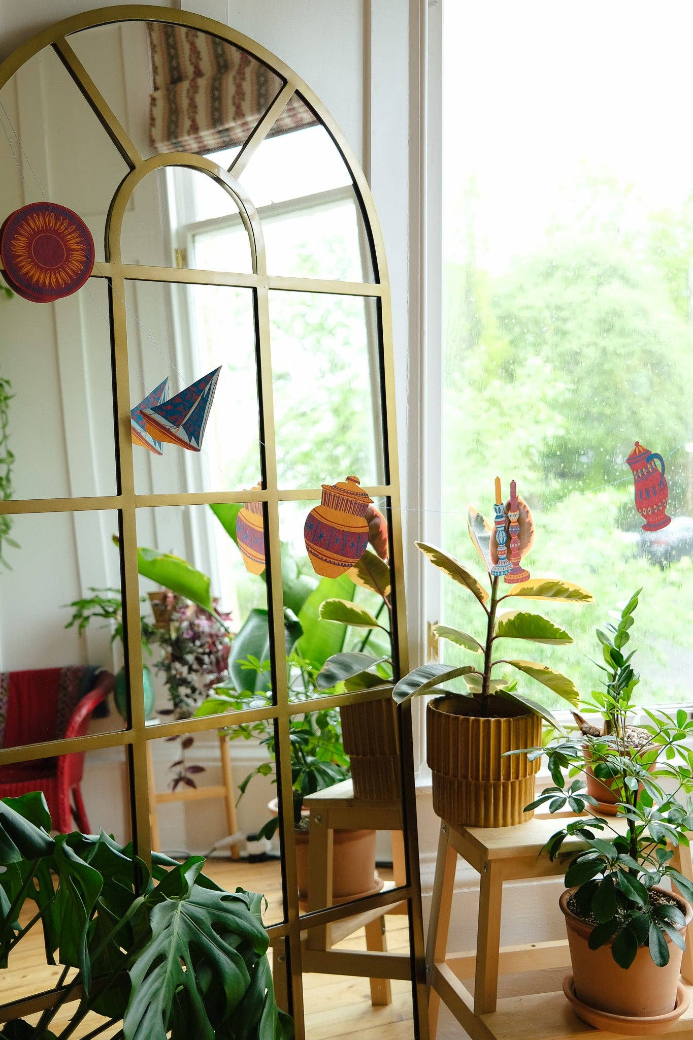 Decorative mirror with a paper garland in a room with plants.