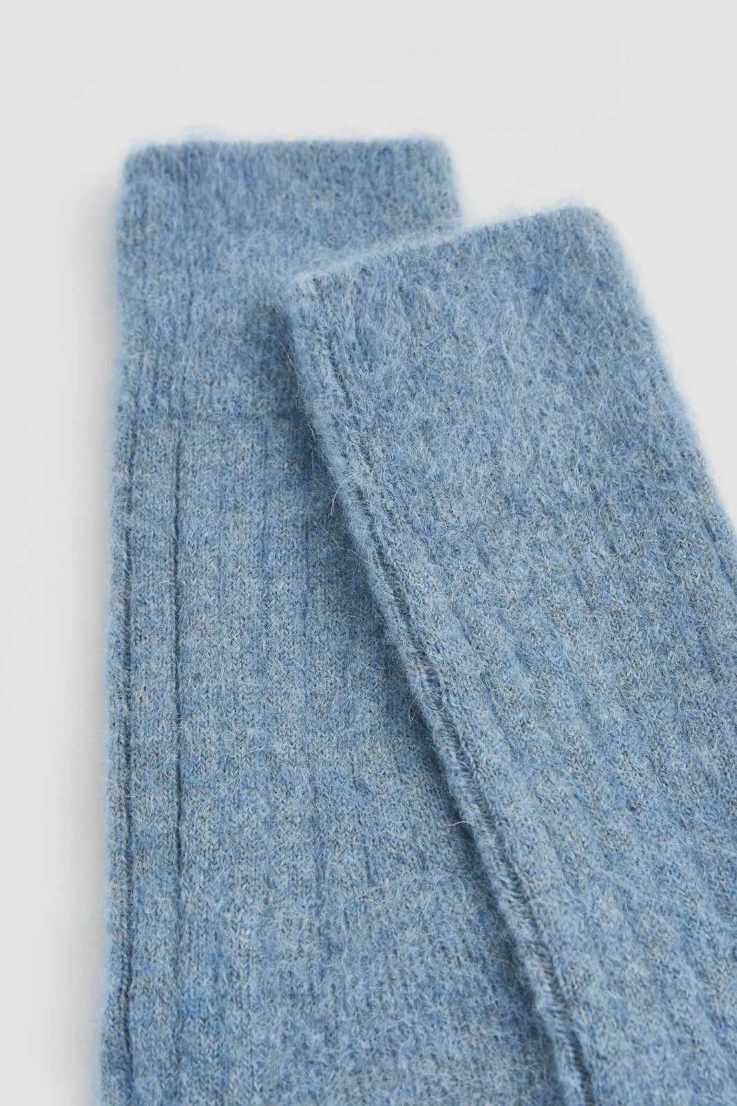 Pair of blue knitted socks on a white background.