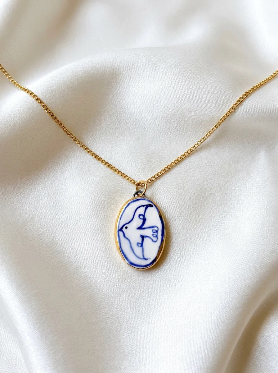 Necklace with a blue and gold pendant on a white fabric background.