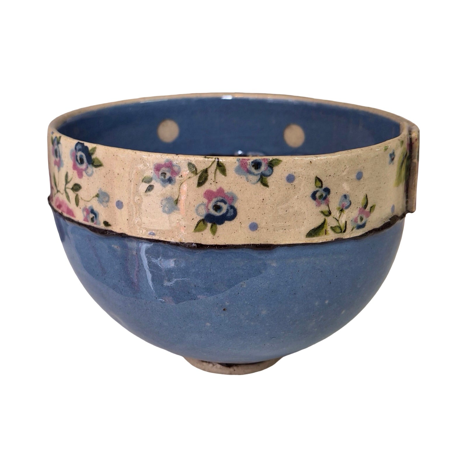 Blue ceramic bowl with floral-patterned top on a white background, with polka dots inside.