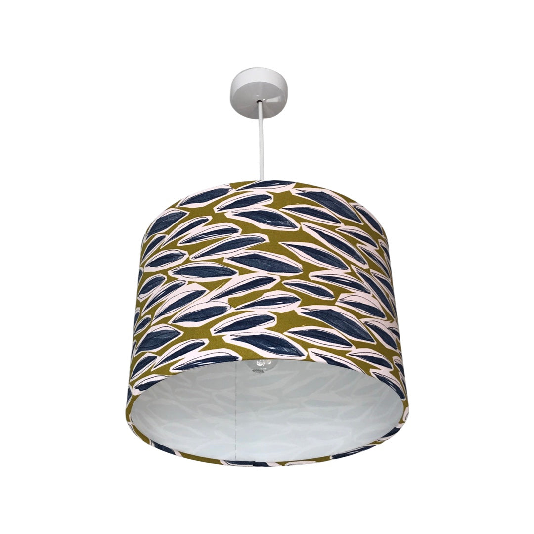 Drum lampshade covered in lime green coloured linen with blue grass dashes hanging in a grey room.