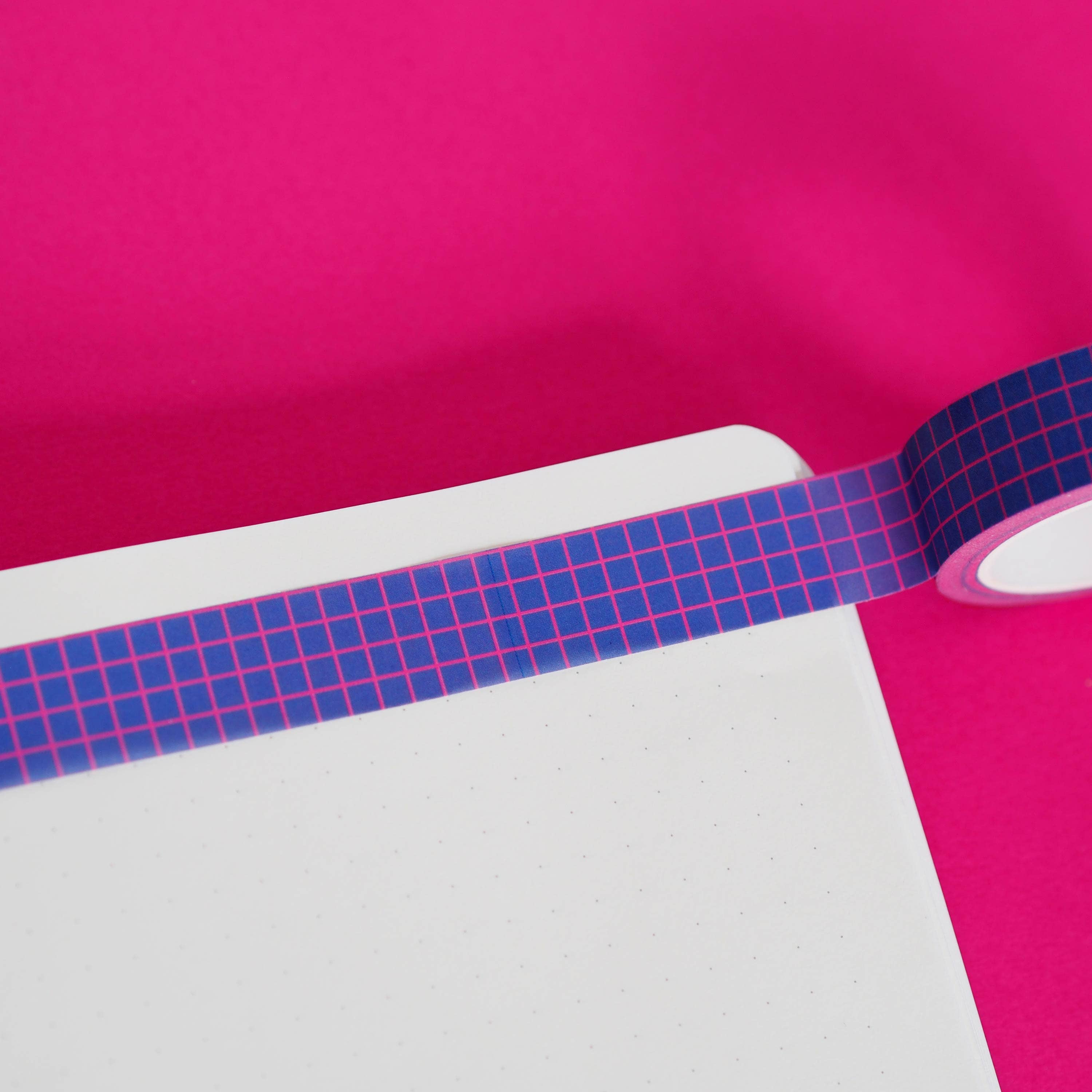 Blue grid-patterned tape on a pink and white background.