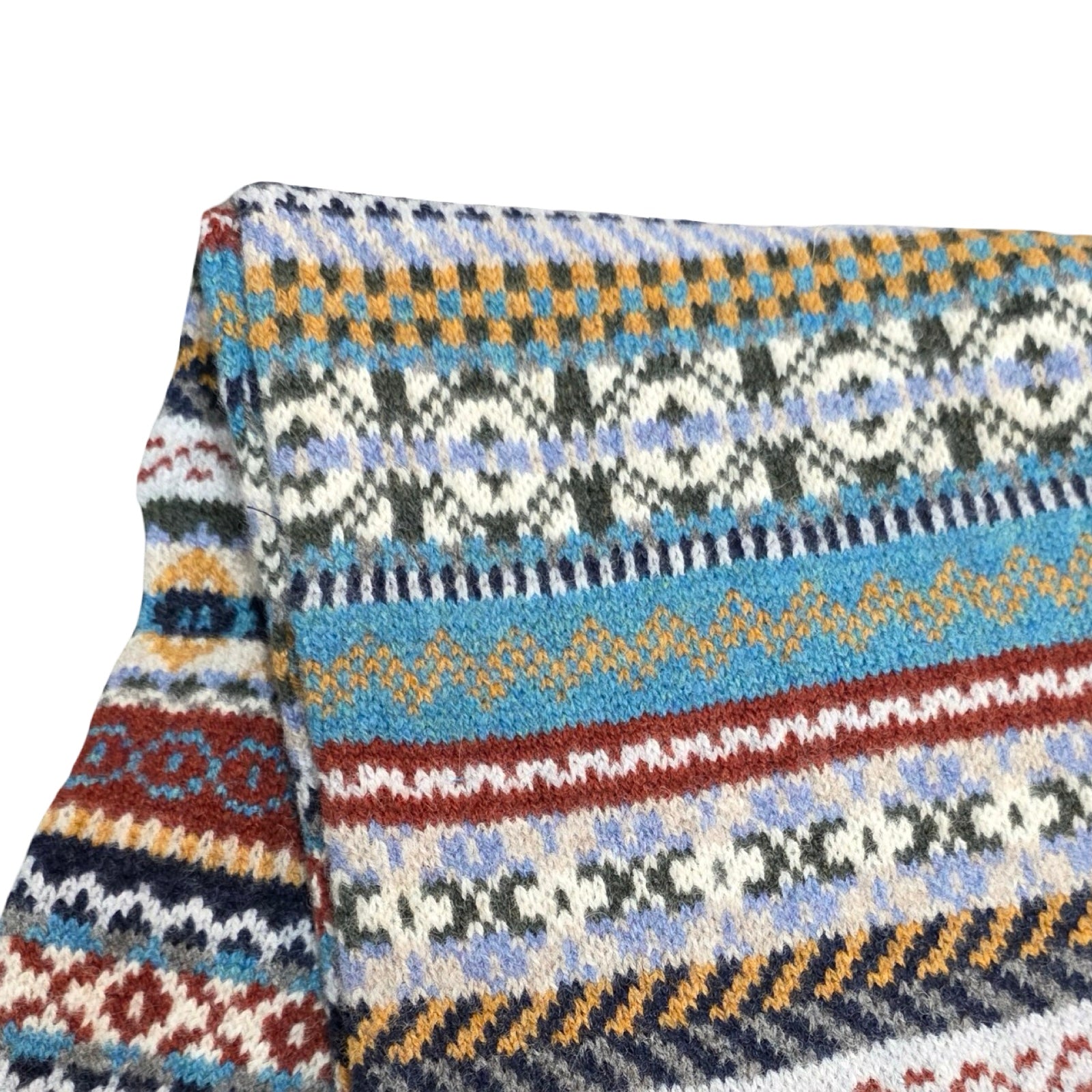 Close-up of a knitted fabric with a colourful pattern on a white background.
