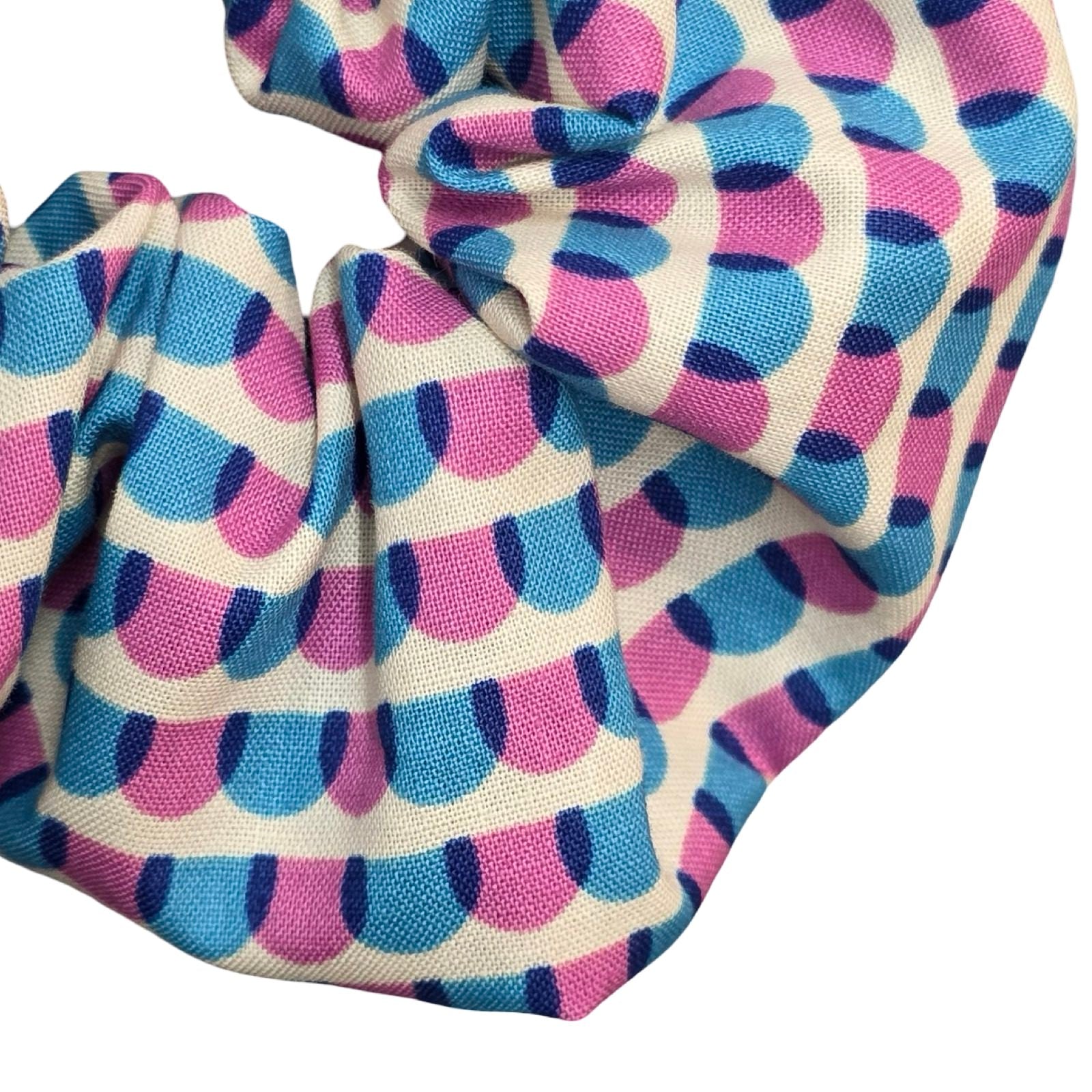 This handmade hair scrunchie is made from 100% cotton fabric with a blue and pink scalloped pattern.