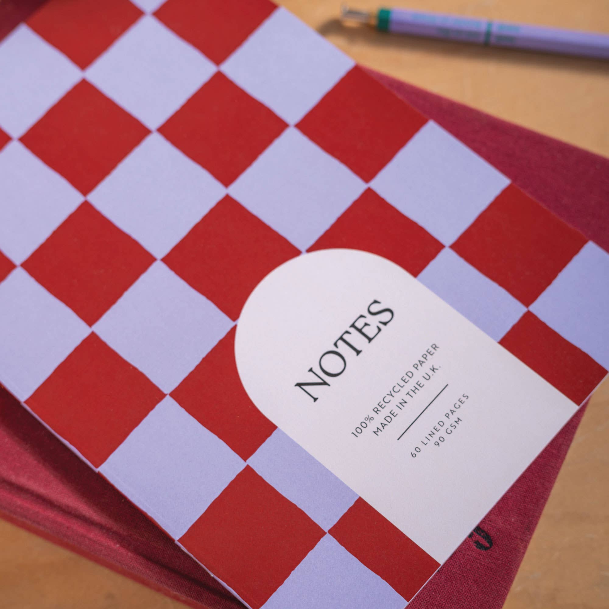 Red and blue checkered notebook with 'NOTES' label on a wooden surface.