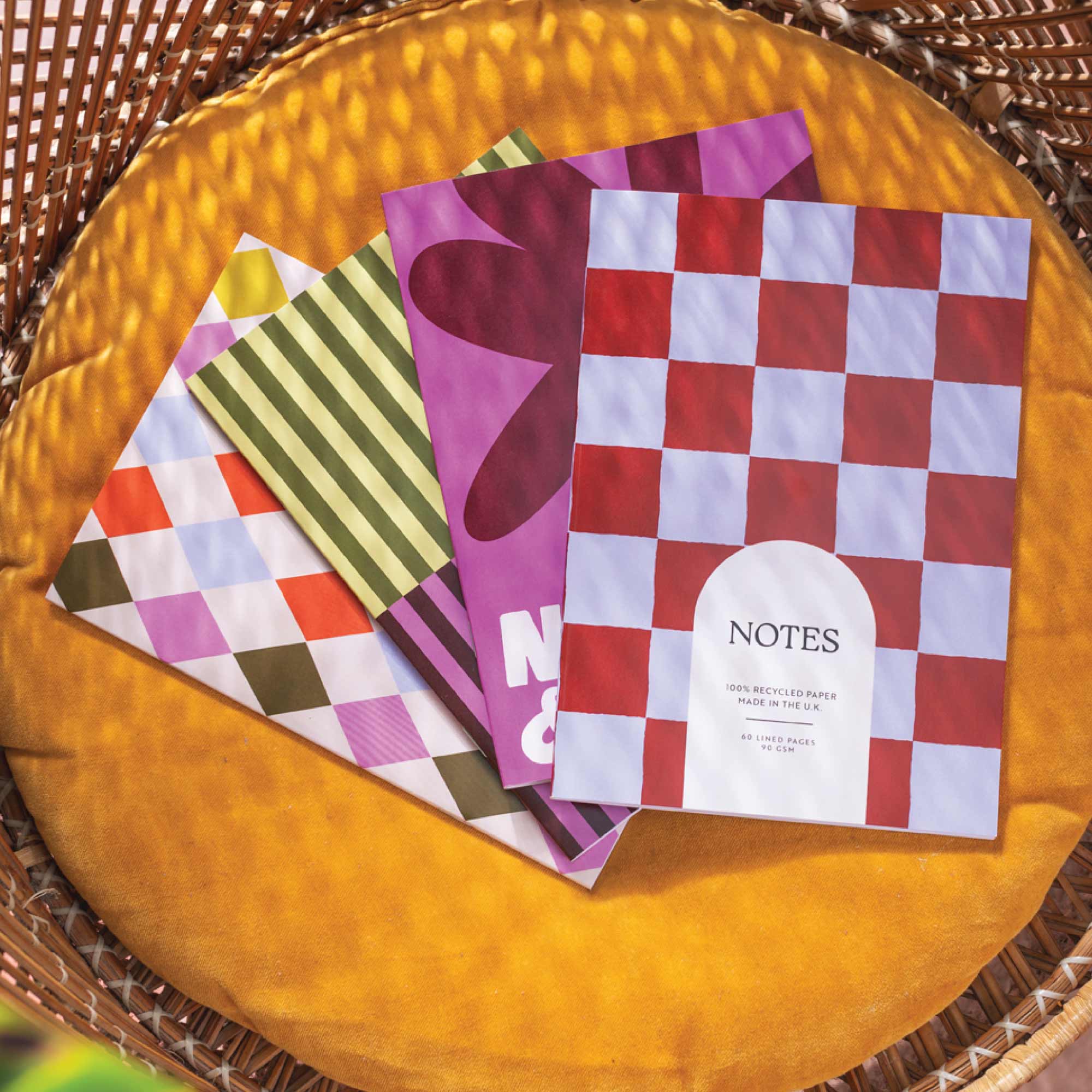 Colourful patterned notebooks on a textured surface.