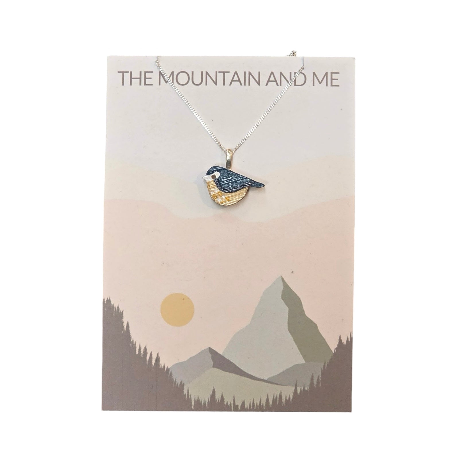 This wooden bird-shaped pendant necklace has a blue tit painted pendant and a sterling silver chain on a branded backing card.