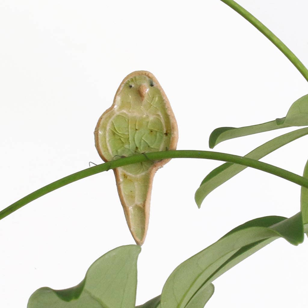 Decorative ceramic bird-shaped hook on a plant with a white background.