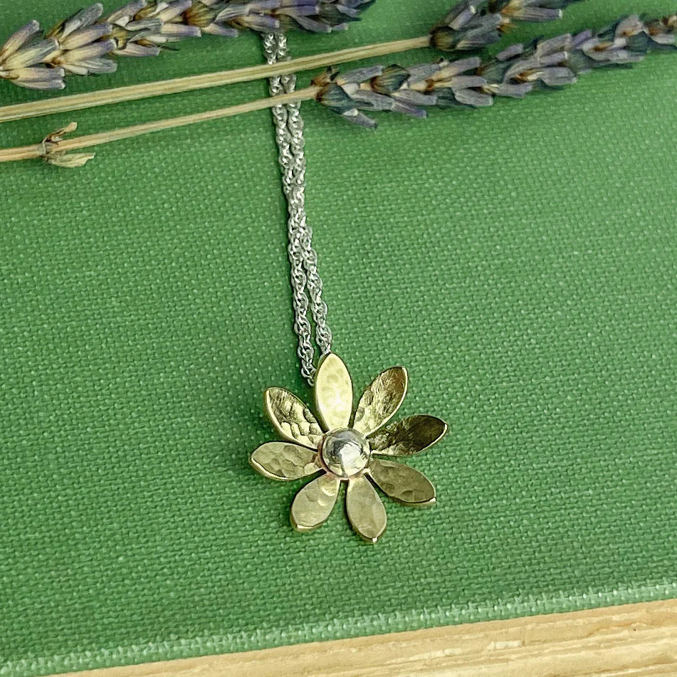 Gold flower-shaped necklace on a green background.