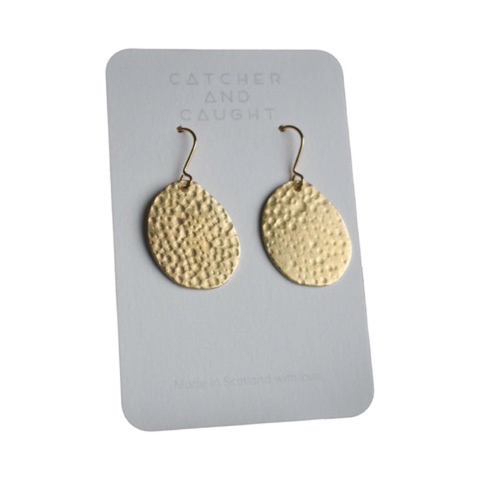 Photo of two hammered, brass loop earrings on backing card.
