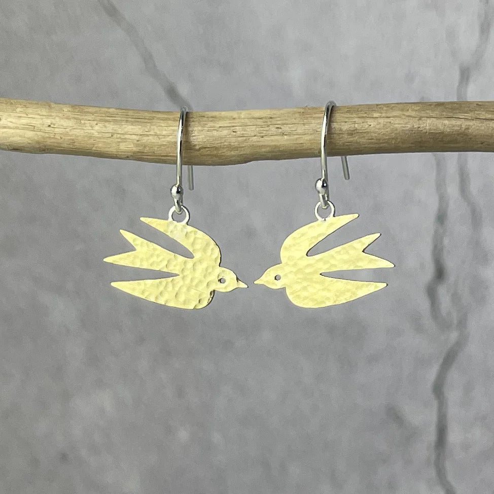 Gold bird-shaped earrings on a gray background.