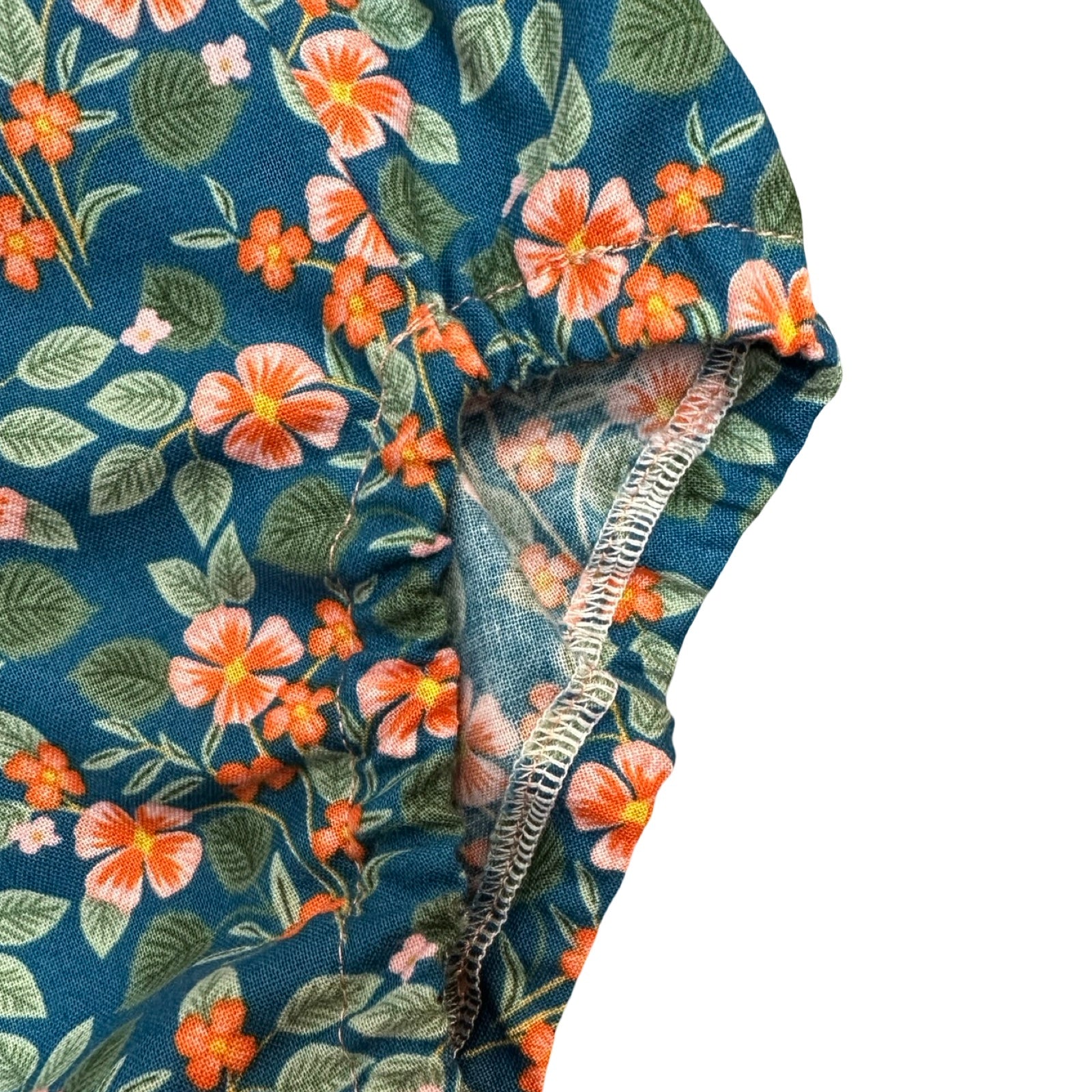 Floral patterned romper with orange flowers on a blue background.