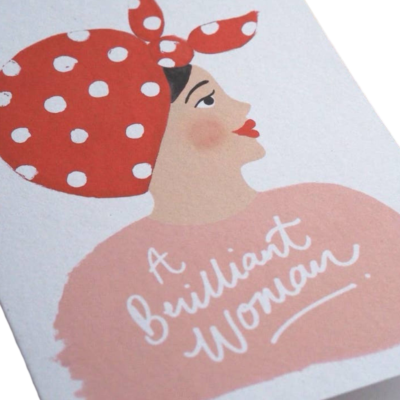 A card featuring a side profile of a girl with black hair wearing a pink jumper and a red and white polka dot scarf in her hair, with the text "A Brilliant Woman". 