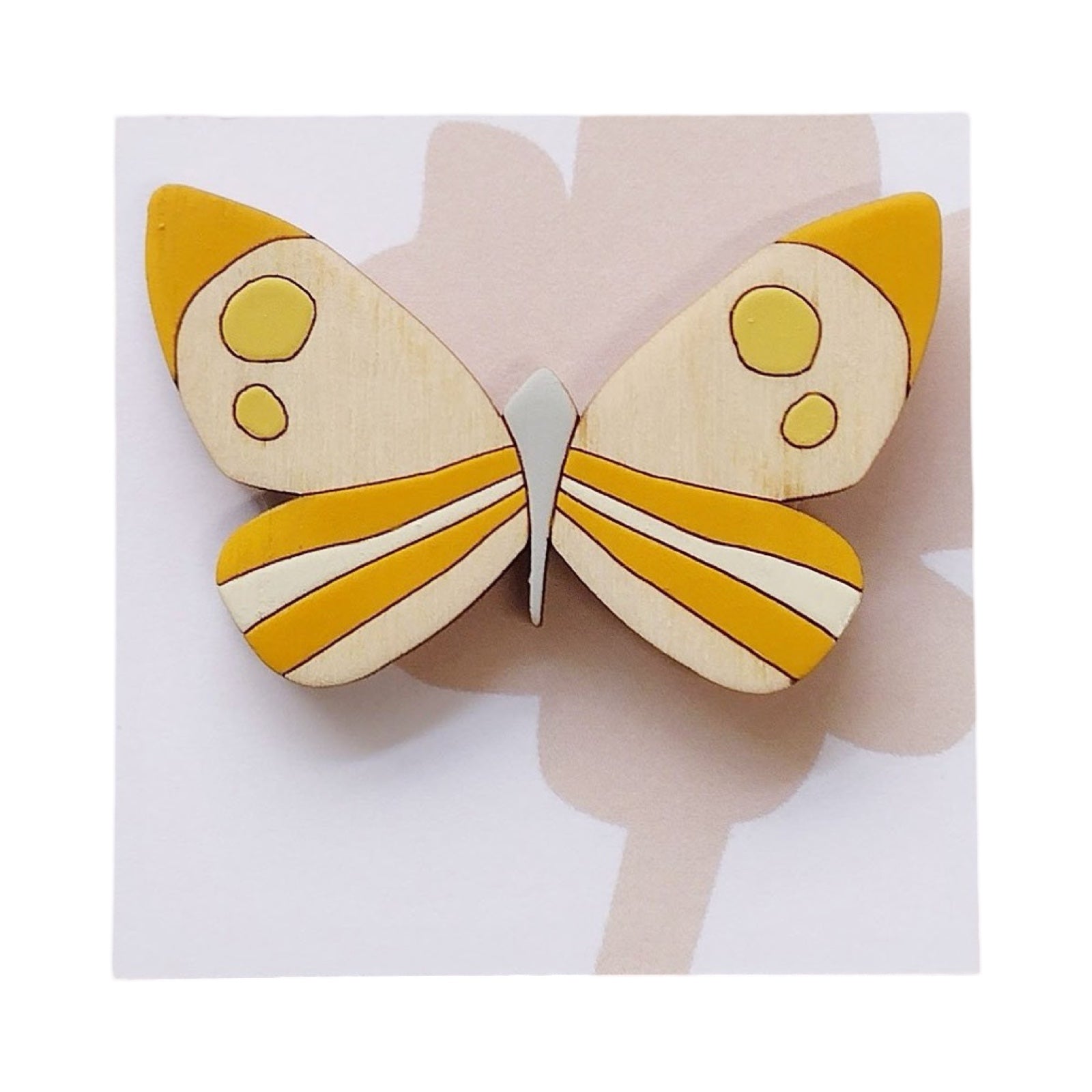 A brimstone butterfly wooden brooch, and-painted with colourful wings in orange, yellow and cream on a white backing card.