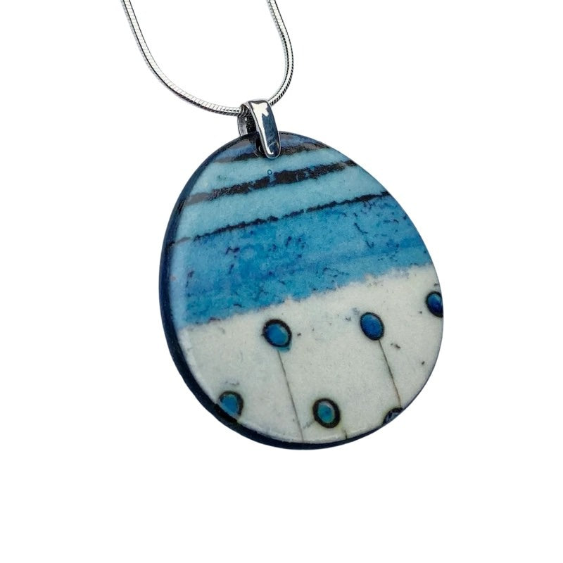 Oval porcelain pendant necklace with an abstract design inspired by nature, in turquoise, cream and black on an 18-inch sterling silver chain.