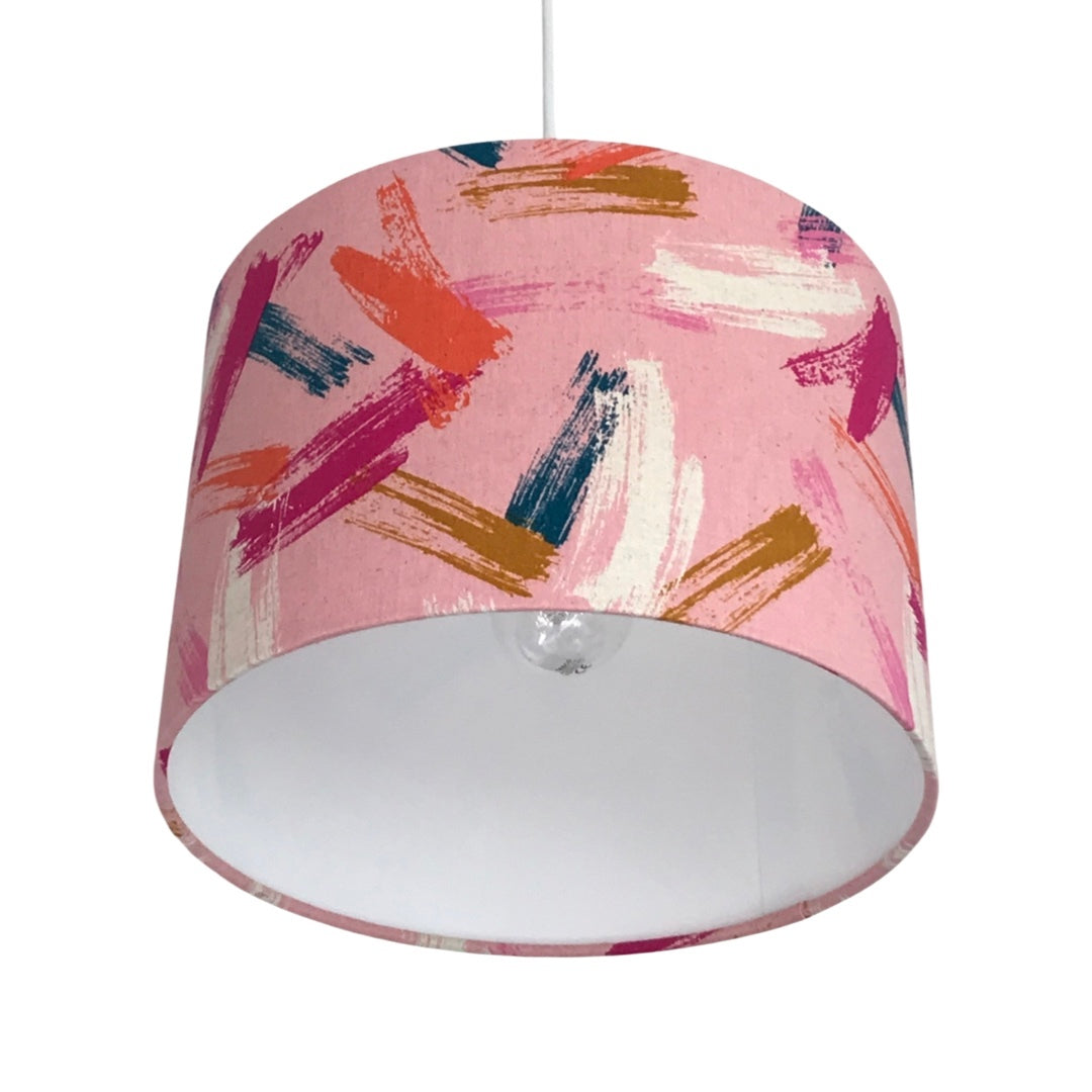 Drum lampshade covered in pink canvas fabric with brush strokes in navy, pink, white, red and brown