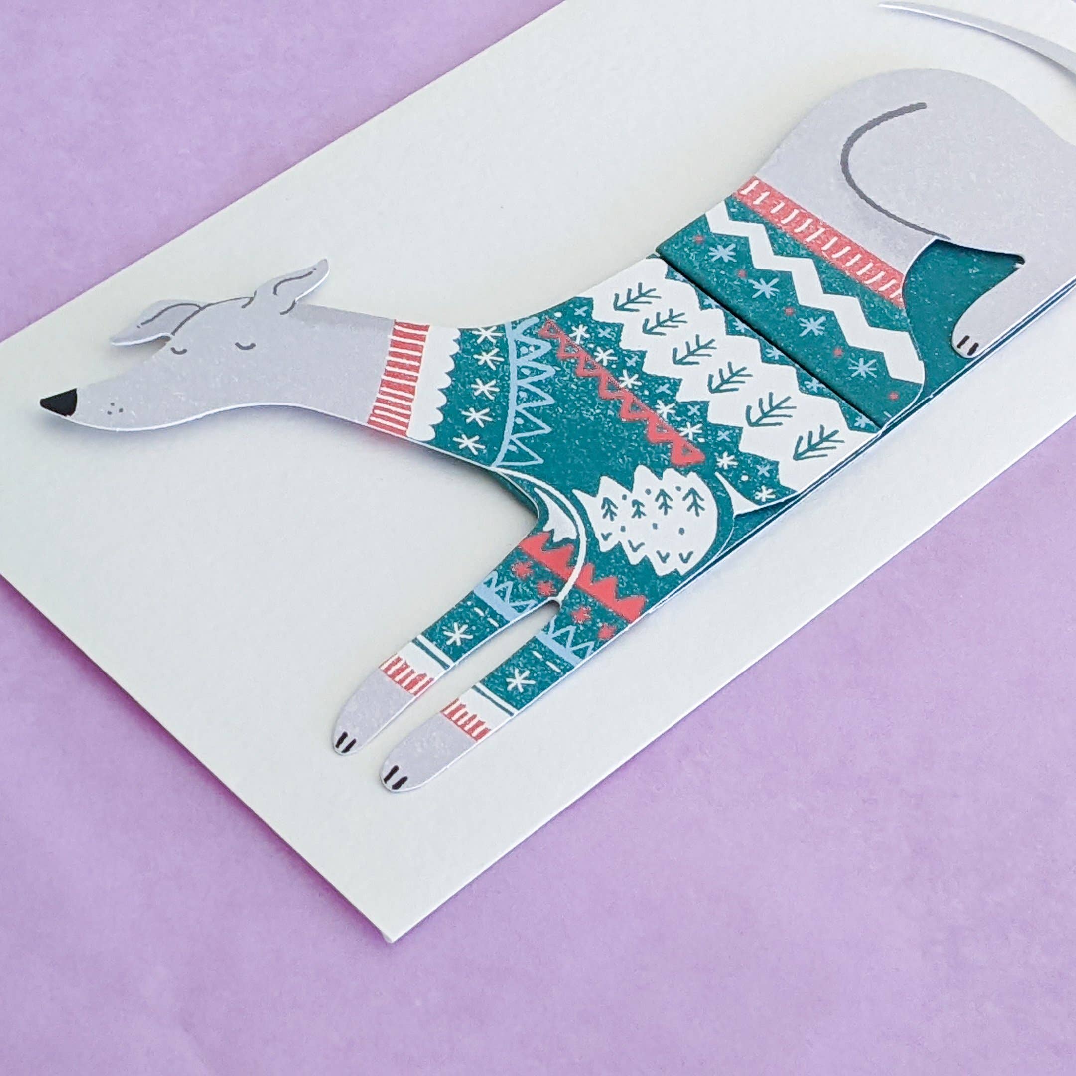 Card with a dog design wearing a patterned sweater on a purple background.