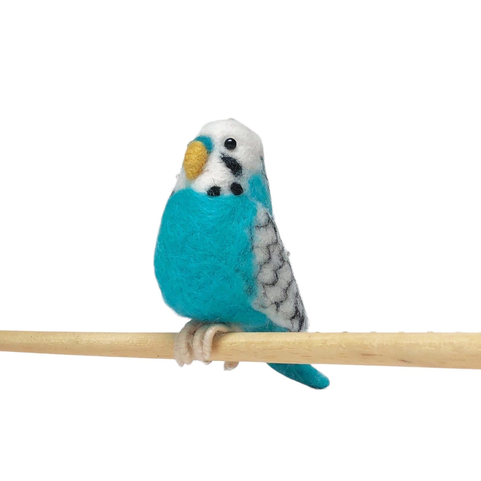 A blue felted budgie sitting on a cane.