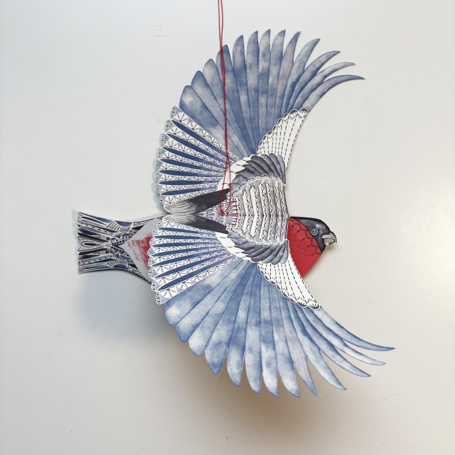Decorative bird ornament with blue and red details on a white background.