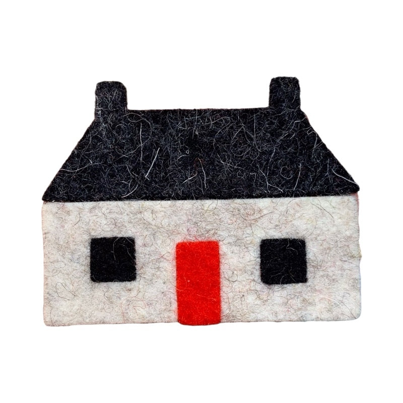 Felt brooch of a traditional Scottish but 'n' ben featuring a white structure with a black roof and windows and a red door.