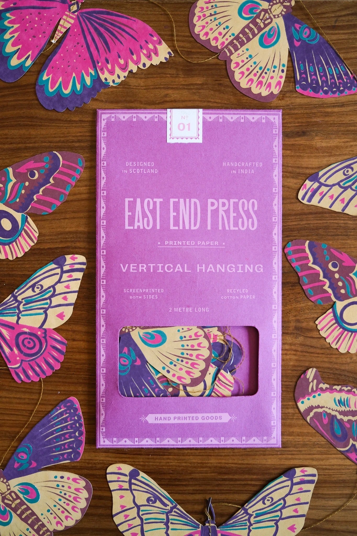 Purple packaging of East End Press with colorful butterfly designs on a wooden surface.