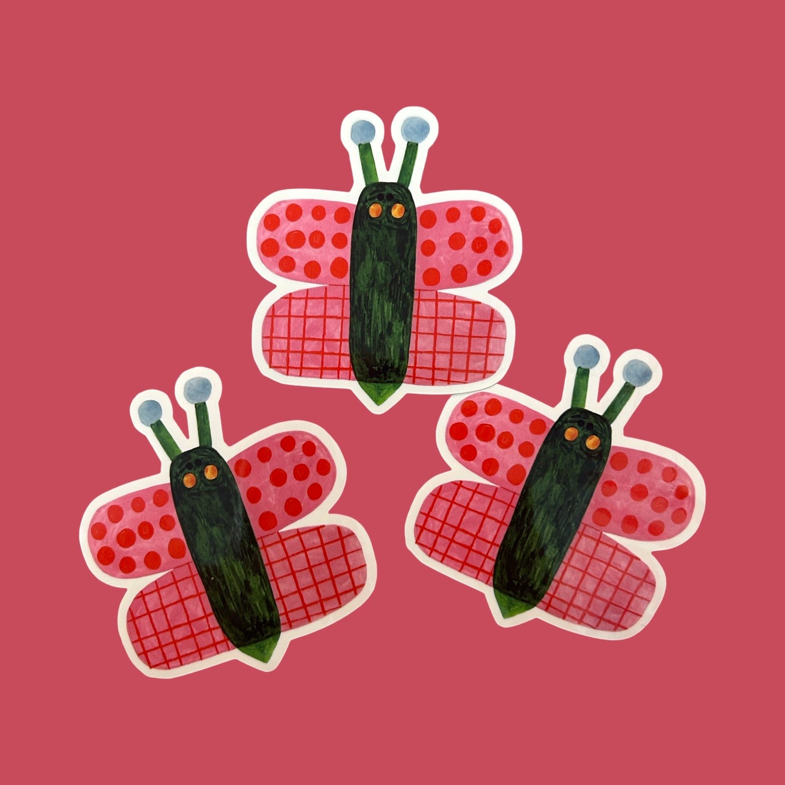 Three hand-drawn style butterfly stickers arranged on a solid pink background. The butterflies feature red patterned wings with white borders, dark green bodies, and light blue antennae.