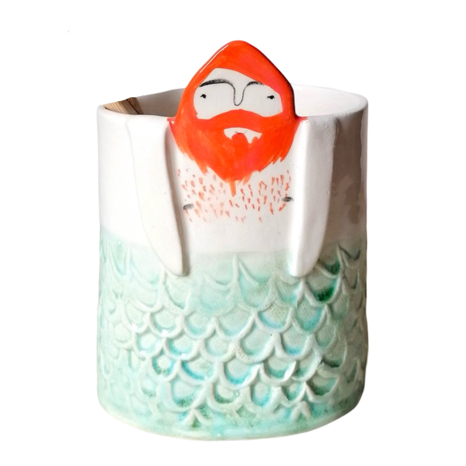 A handmade ceramic pot with pale green mermaid scales and a man's head with ginger hair and a beard.