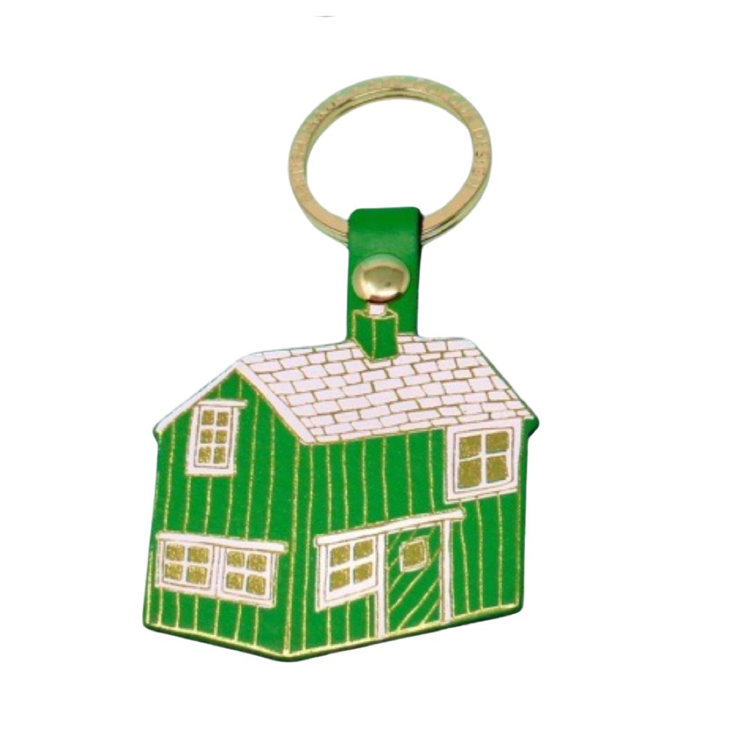 A green cabin shaped keyring with white windows and a white roof on a gold ring.