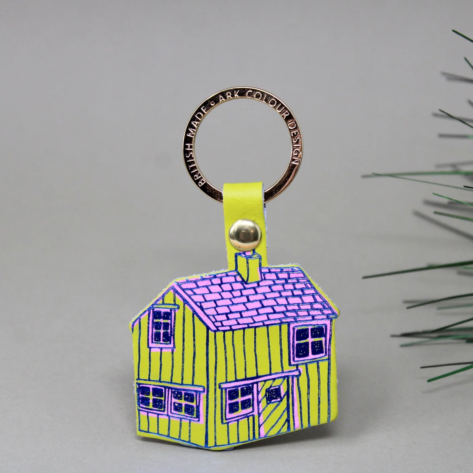 House-shaped keychain with a colorful design on a grey background