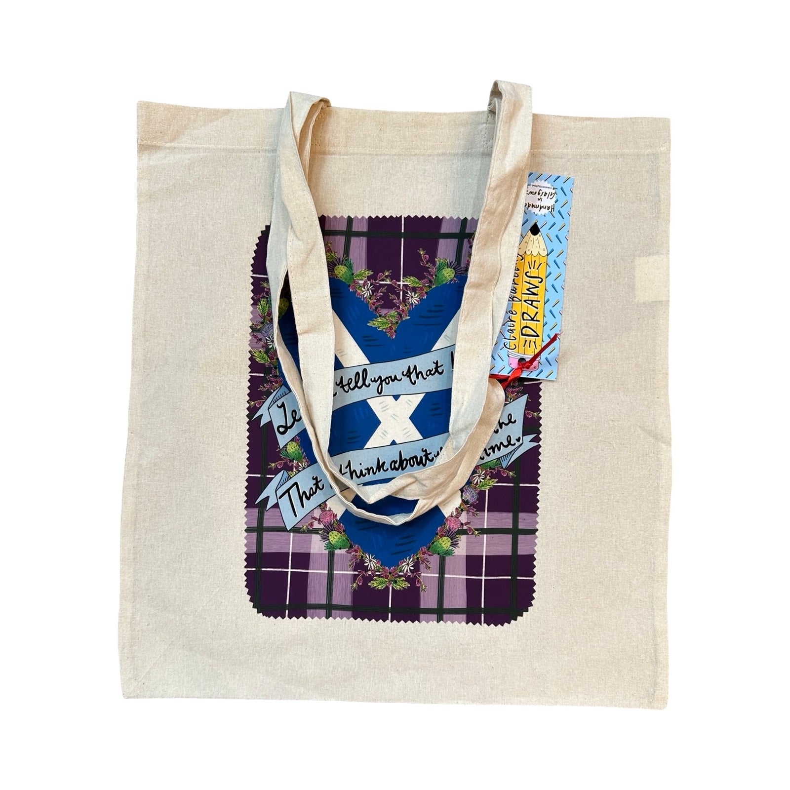 Tote bag with the lyrics 'Let me tell you that I love you, that I think about you all the time' from the song Caledonia, written in banners across a saltire heart, on a purple tartan background. 